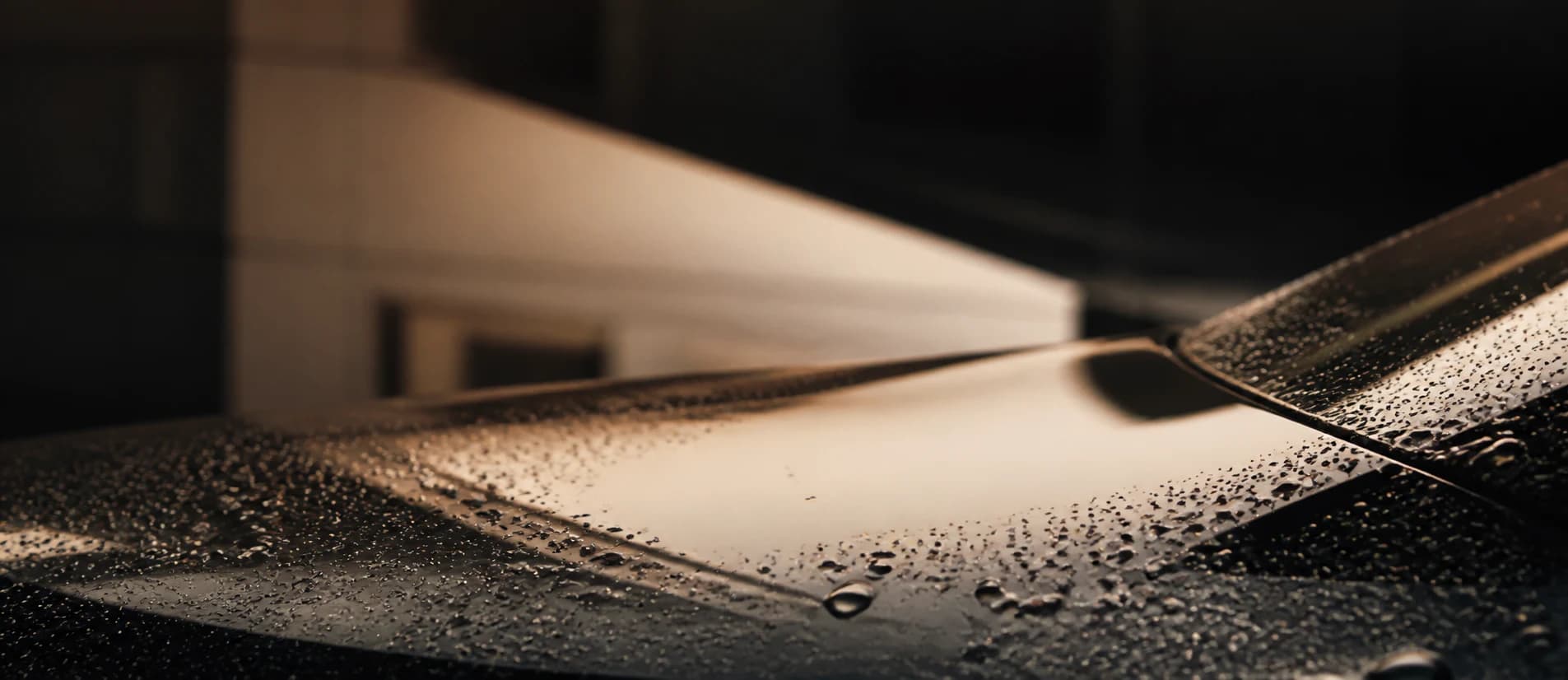 Water beading across a freshly finished black vehicle